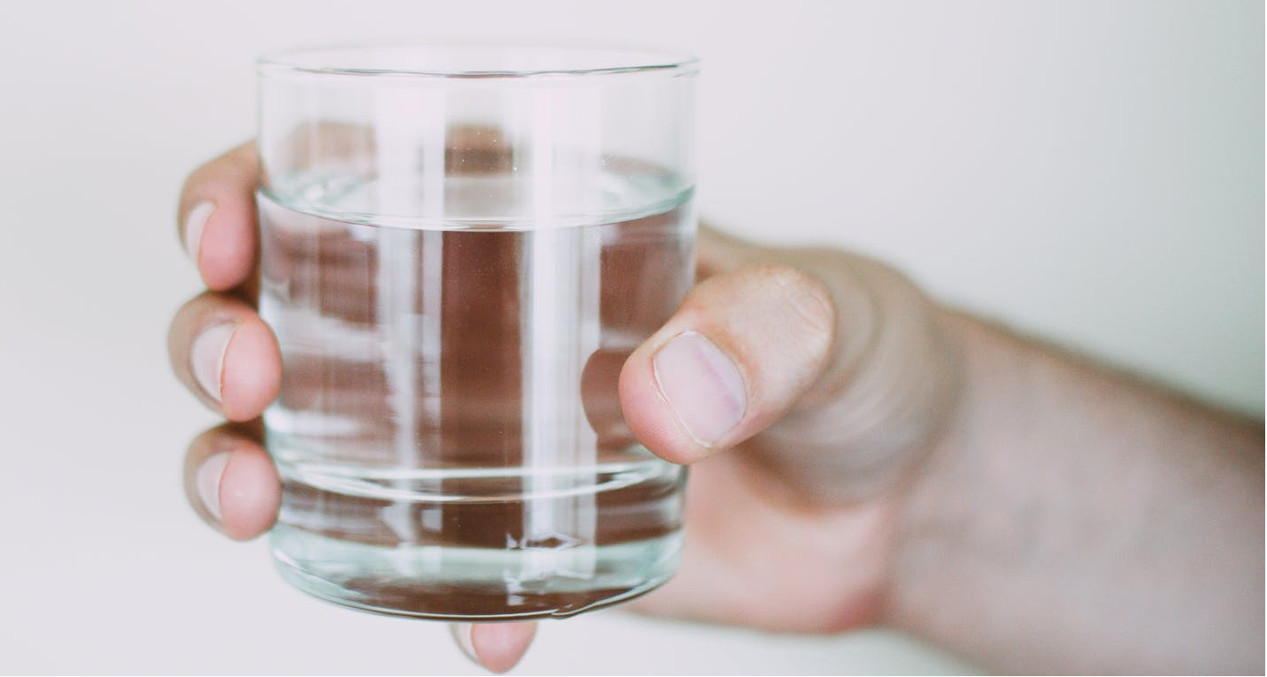 A person holding a glass of purified water